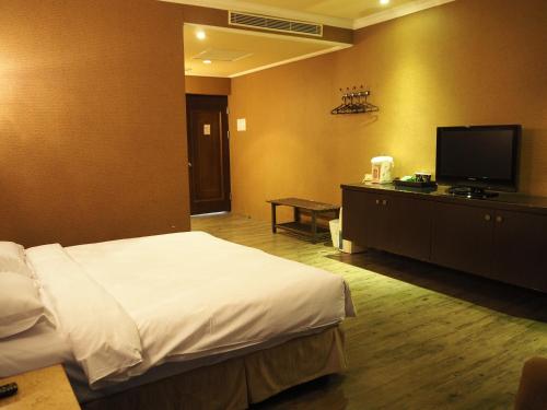 a hotel room with a bed and a flat screen tv at The Riverside Hotel & Motel in Kaohsiung