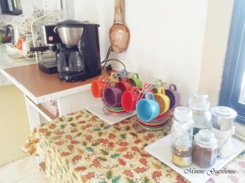 a group of cups on a table next to a coffee maker at Minine Guesthouse in Silang