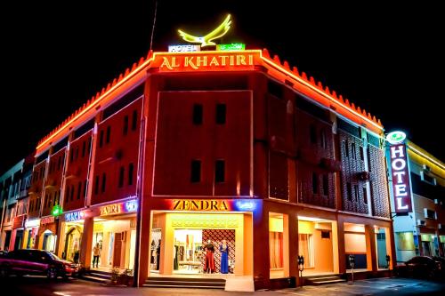 a red brick building with a neon sign on the side of it at Al Khatiri Hotel in Kubang Kerian