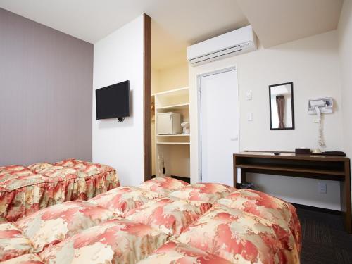 a hotel room with two beds and a television at Osaka Academia in Osaka