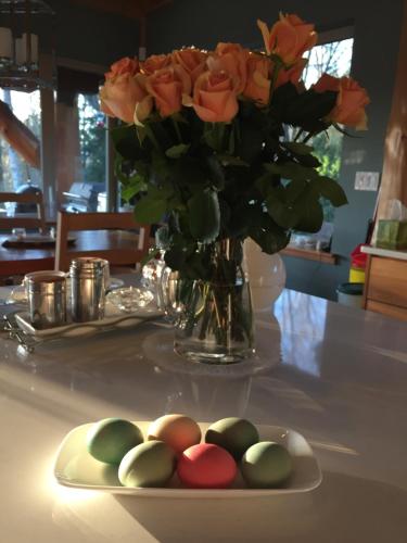a plate with colored eggs on a table with a vase of roses at The Rockwell-Harrison Guest Lodge in Harrison Hot Springs