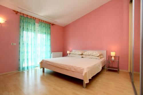 a bedroom with a bed and a pink wall at Apartman Dinka in Trogir