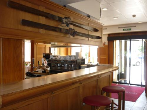 a bar with two red stools in a kitchen at Hotel de la Lande in Le Brassus