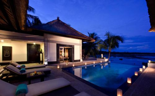 a villa with a swimming pool at night at Banyan Tree Bintan in Lagoi