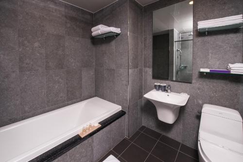 bagno con vasca, lavandino e servizi igienici di Hotel Leo a Jeju