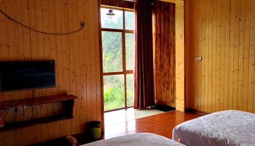 a bedroom with a bed and a television and a window at Zhangjiajie one step to heaven inn (Yangjiajie ticket office) in Zhangjiajie