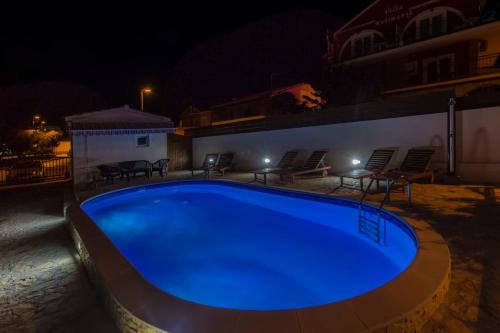 a large blue swimming pool at night at Apartmani Mariva in Vodice