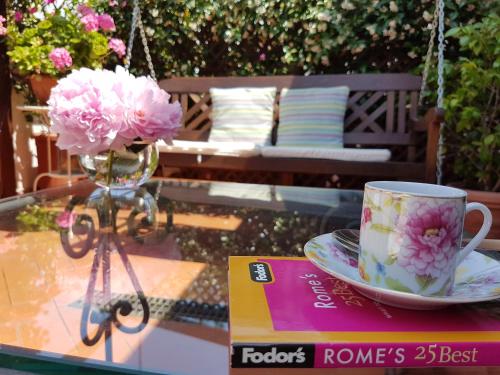 a glass table with a coffee cup and a plate of flowers at Althea Inn Roof Terrace in Rome