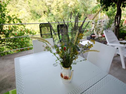 a white table with a vase of flowers on it at Apartments Vesela in Janjina