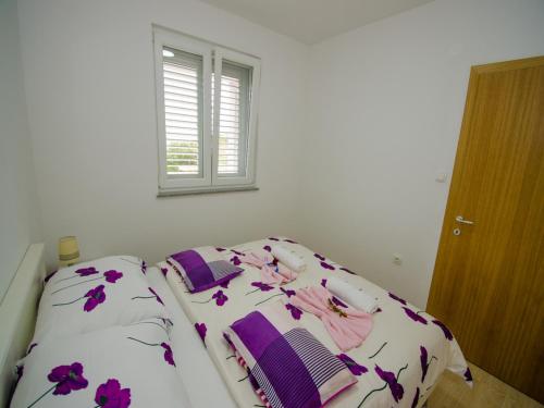 a bedroom with a bed with purple flowers on it at Apartments Vesela in Janjina