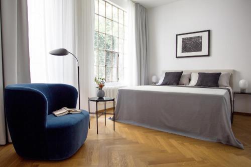 1 dormitorio con 1 cama y 1 silla azul en August The Boardinghouse, en Hamburgo