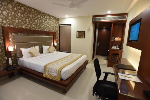 a bedroom with a bed and a desk and a television at Hotel Grand Rajputana in Raipur