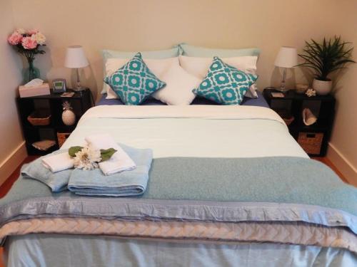 a bed with blue and white pillows and flowers on it at Riverbend Suite Rooms in Rosebank