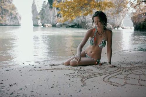 a woman in a bikini drawing in the sand on a beach at KRABI BAMBOO KINGDOM at AOLUEK PARADISE in Ao Luk