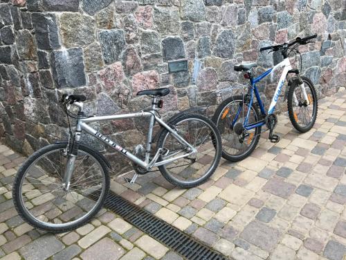 two bikes are parked next to a stone wall at Dzirnavkalns in Cesvaine