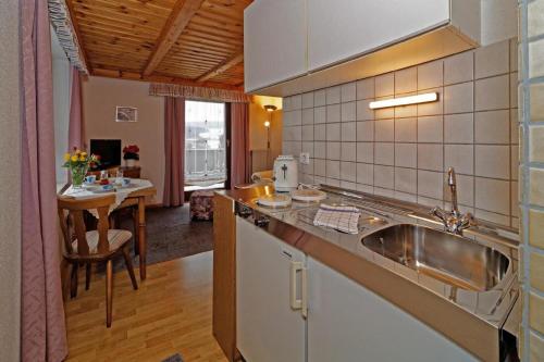a kitchen with a sink and a table in a room at Berghof Pension und Ferienwohnungen in Bischofsmais