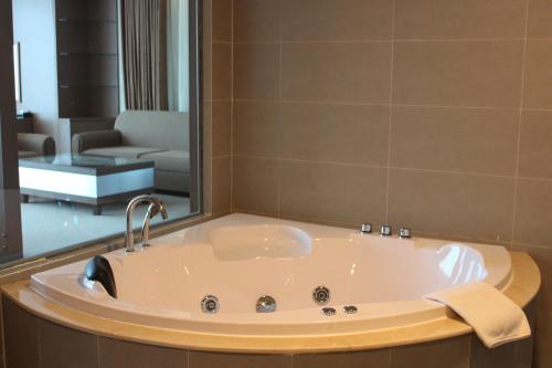 a bath tub in a bathroom with a living room at Muong Thanh Grand Tuyen Quang Hotel in Tuyên Quang