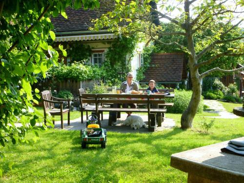 two people sitting at a picnic table with a dog at Altes Gehöft am Lormanberg in Kirchberg an der Raab