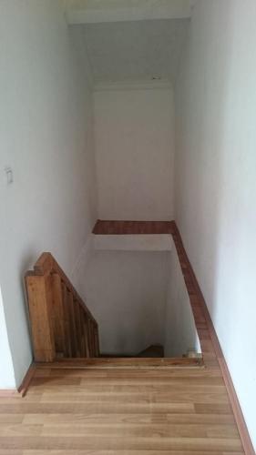 an empty room with a white wall and wooden floors at N&N Guest House in Mestia