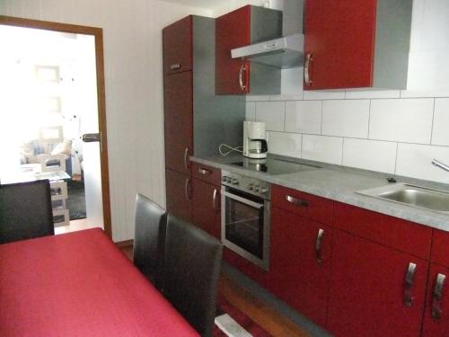 a kitchen with red cabinets and a red table and chairs at Ferienwohnung Morgen in Valwig