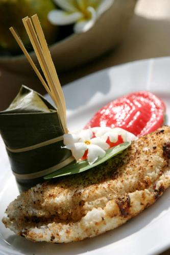 a plate with a piece of fish and a strawberry at Sarasvati Borobudur in Borobudur