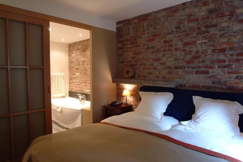 a bedroom with a bed and a brick wall at Charmehotel Manoir Ogygia in Poperinge