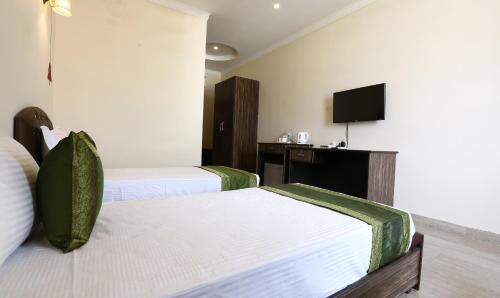 a hotel room with two beds and a flat screen tv at Treebo Blessing Bells in Dehradun