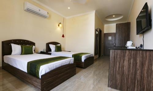 a hotel room with two beds and a flat screen tv at Treebo Blessing Bells in Dehradun