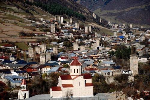 a small town with a church and a mountain at N&N Guest House in Mestia