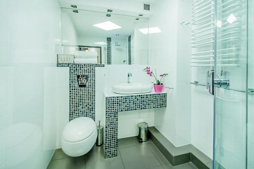 a white bathroom with a sink and a toilet at Angel City Center Krakow Aparthotel in Krakow