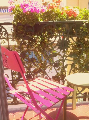 a pink chair sitting next to a table and flowers at Hôtel Brimer Cannes in Cannes
