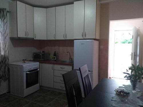 a kitchen with a table and a white refrigerator at Apartmani Cuce in Kotor