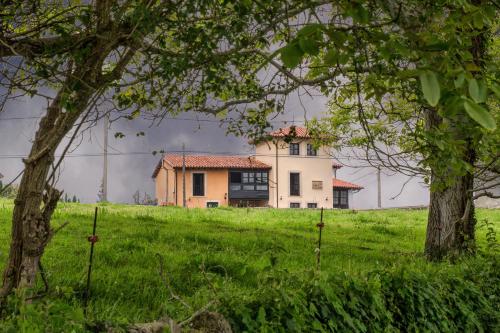 ein Haus auf einem Hügel mit Bäumen im Vordergrund in der Unterkunft Casa Rural Gallu Juancho in Gobiendes