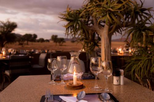 a table with wine glasses and a candle on it at Sossusvlei Lodge in Sesriem