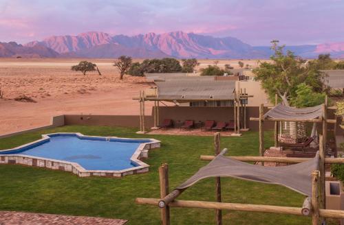 a house with a swimming pool in the middle of the desert at Sossusvlei Lodge in Sesriem