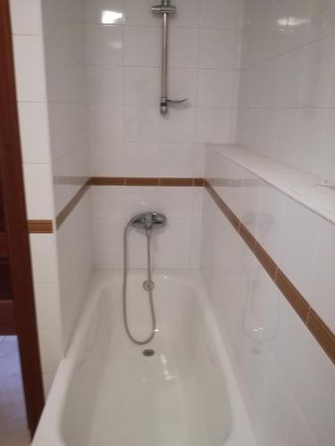 a white bath tub with a shower in a bathroom at APARTAMENTOS POBRA-CASTELO in A Pobra do Caramiñal