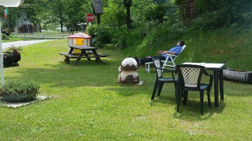 a person sitting in a chair at a table in a yard at Agriturismo al Marter in Ledro
