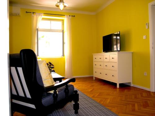 a yellow living room with a chair and a television at Holiday Home Lija Center in Rab