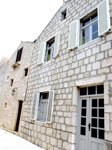 a brick building with white windows and a door at Holiday Home Lija Center in Rab