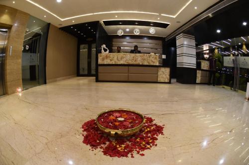 a lobby with a bowl of red flowers on the floor at Hotel Grand Rajputana in Raipur