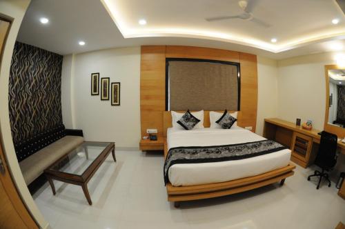 a bedroom with a large bed and a bench in it at Hotel Grand Rajputana in Raipur