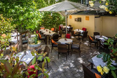 a patio with tables and chairs and an umbrella at BC Hotel Bad Kreuznach mit Restaurant Mühlentor in Bad Kreuznach