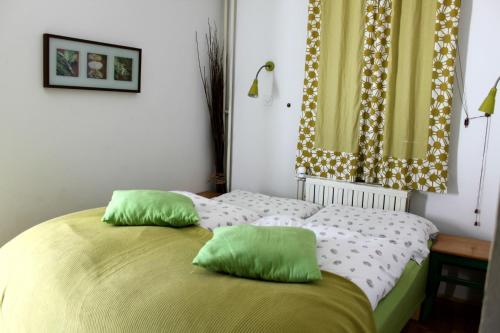a bedroom with a bed with two green pillows on it at House Raduha - depandansa in Luče