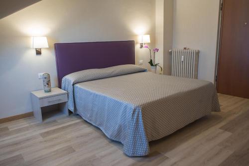 a bedroom with a bed with a purple head board at Hotel Torino Porta Susa in Turin