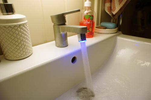 a sink with a faucet with water coming out of it at Berge & Laila's Private Apartment in Førde