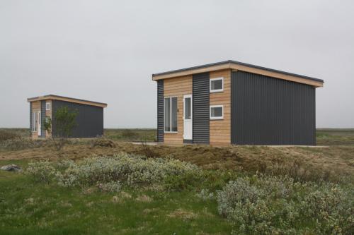 two buildings on a field with grass and bushes at Uxahryggur in Hvolsvöllur