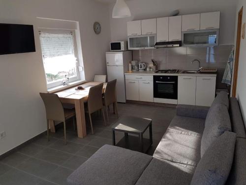 uma cozinha e uma sala de estar com um sofá e uma mesa em Apartman Ante em Seget Vranjica