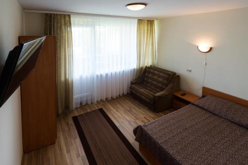a bedroom with a bed and a chair and a window at Pas Roma in Šventoji