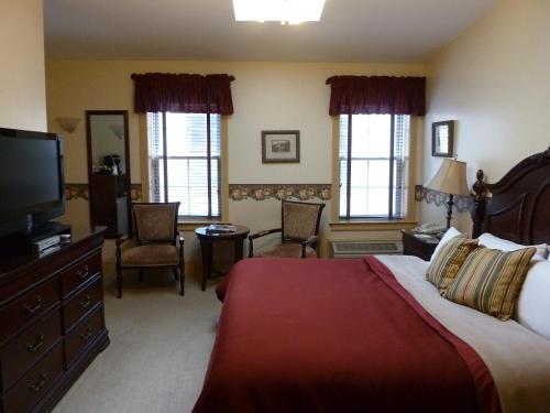 a hotel room with a bed, tv, couch and chair at The Inn at Jim Thorpe in Jim Thorpe