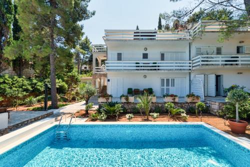 a house with a swimming pool in front of a house at Apartments Tamar in Jelsa